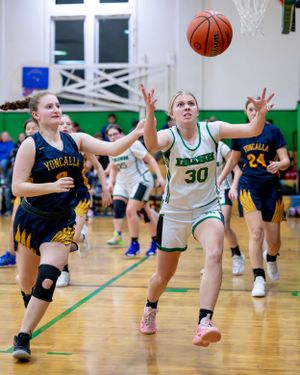Basketball players from opposing teams reach for a loose ball during an intense moment in a high school game.