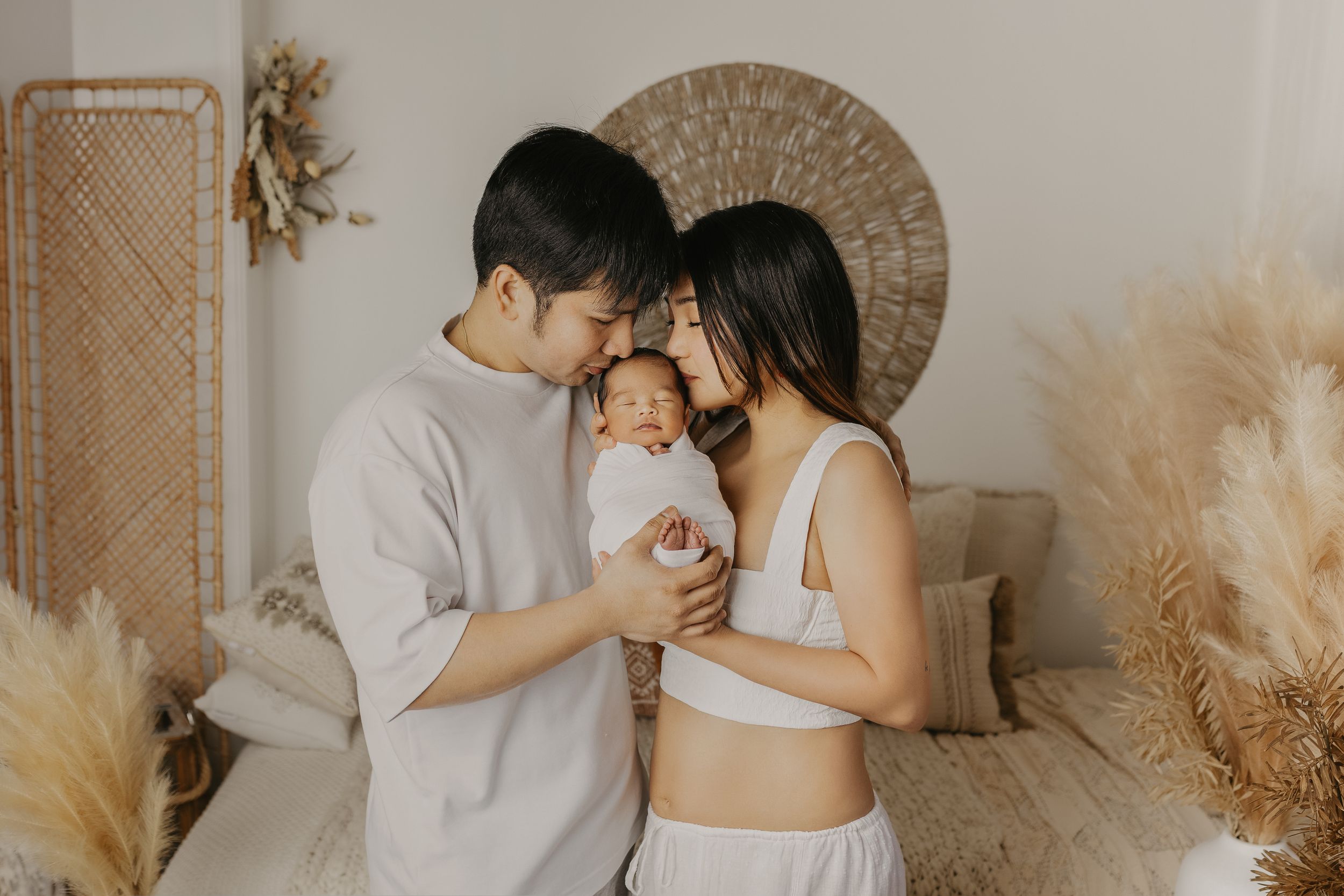 A couple shares intimate moments in a warm neutral-toned studio setting with pampas grass decor.