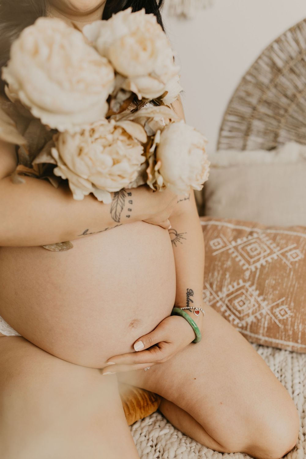 Close-up details of cream roses and lace dress in maternity photoshoot.