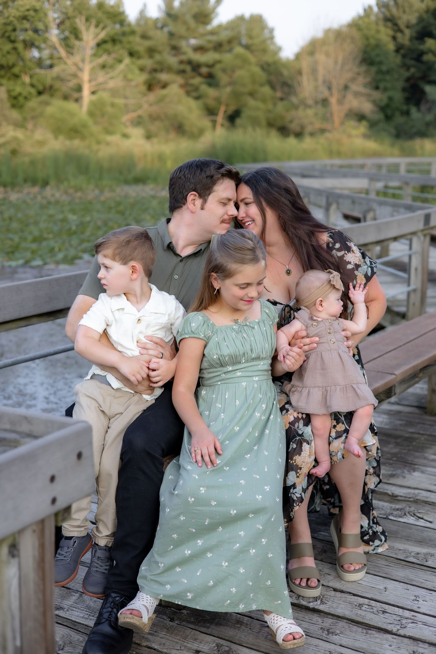 Parents play with their babies outdoors during a casual black and white photo session.