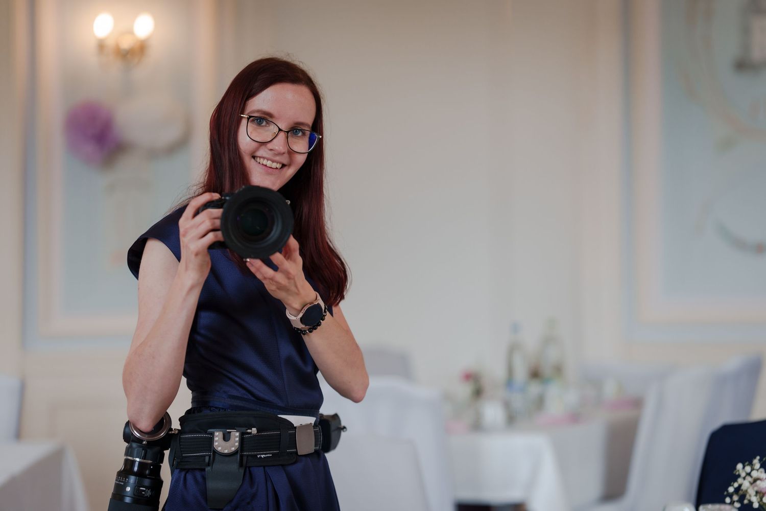 Professional photographer checking camera while working at elegant indoor event.