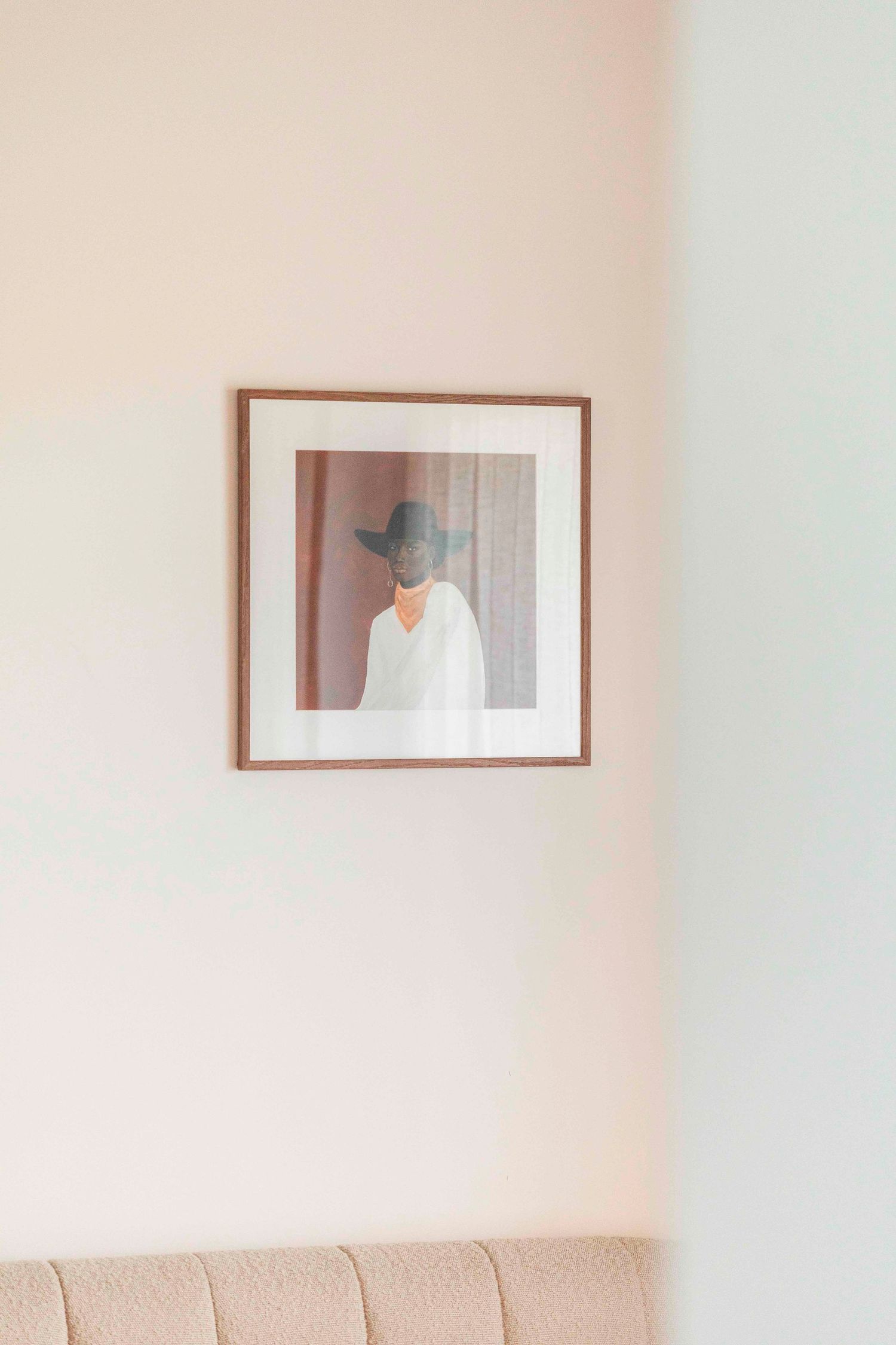 Minimalist framed artwork hanging on a pale pink wall above a sofa.