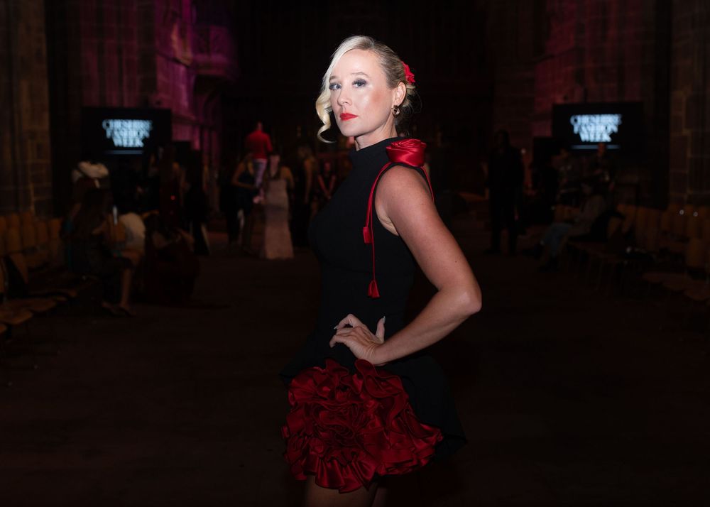 A dancer in a black and red flamenco dress poses dramatically on a dimly lit dance floor.