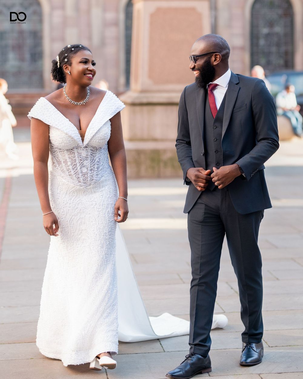A couple in wedding attire poses together outdoors for a series of romantic portraits.