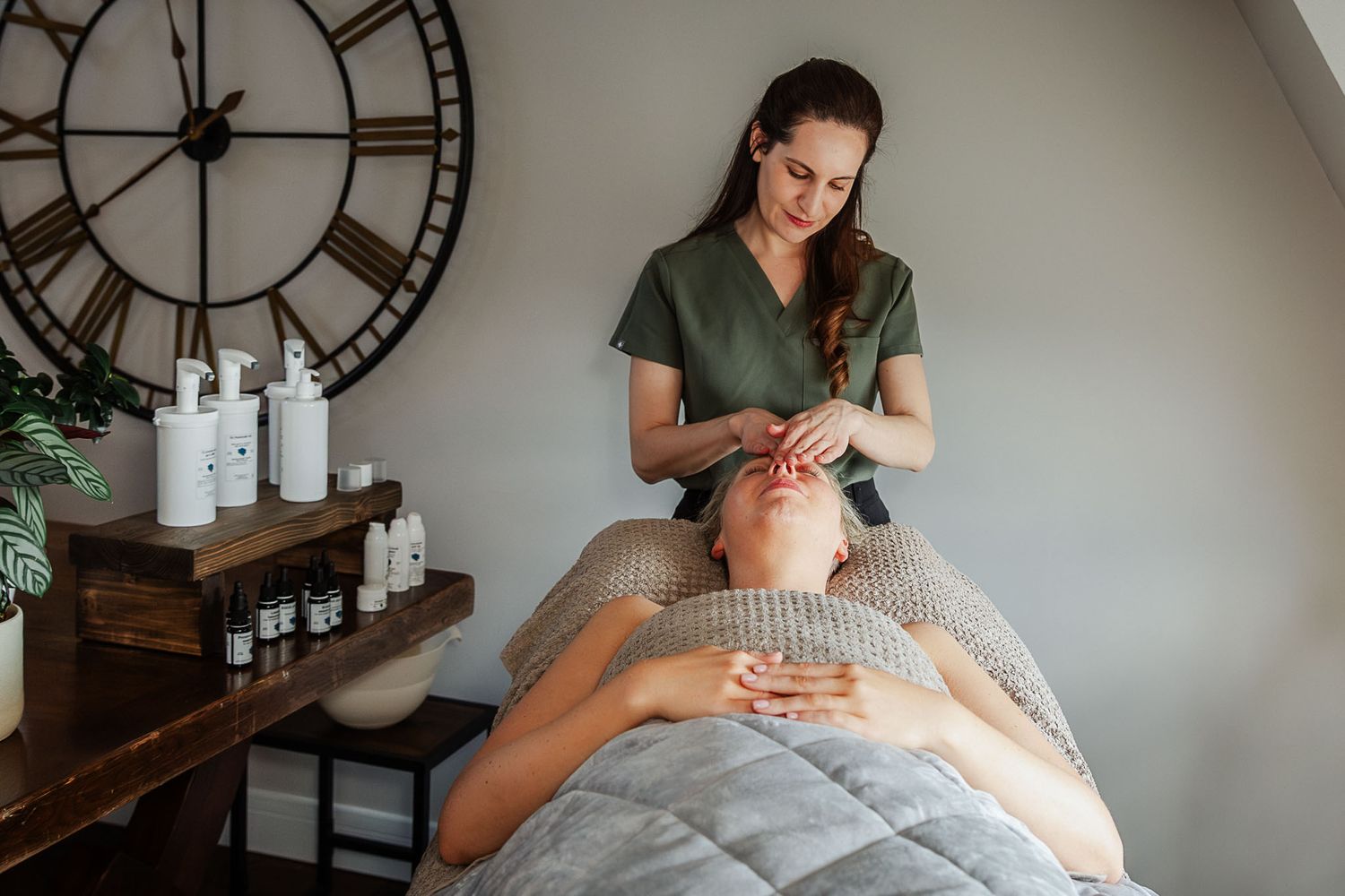 A skin therapist looks natural and relaxed as she gives her client a facial massage in her Clifton clinic during a Bristol brand photoshoot.