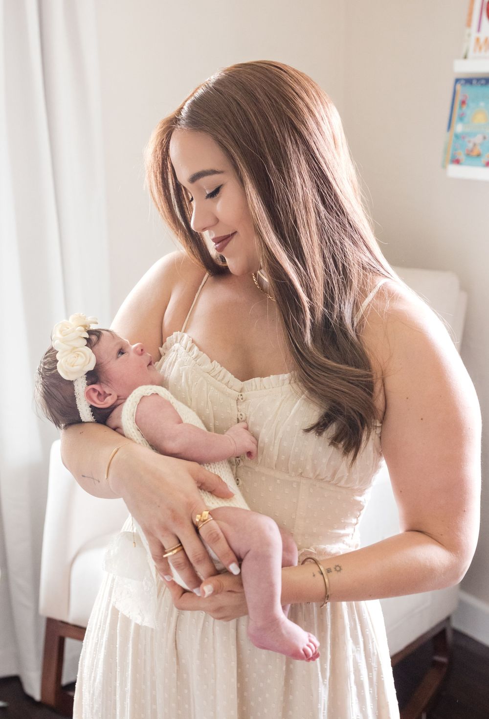 A tender moment captured indoors as a woman in white holds a newborn.