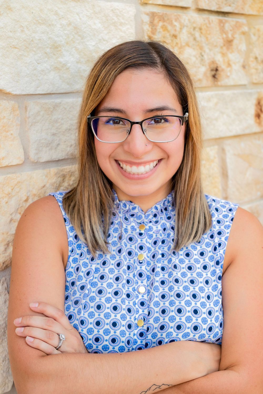 Professional portrait series showing a blue and white patterned sleeveless top against a textured stone wall background.