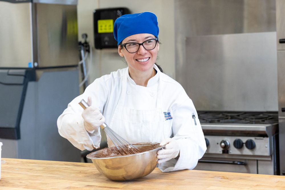 Baking student mixing batter in a large silver bowl