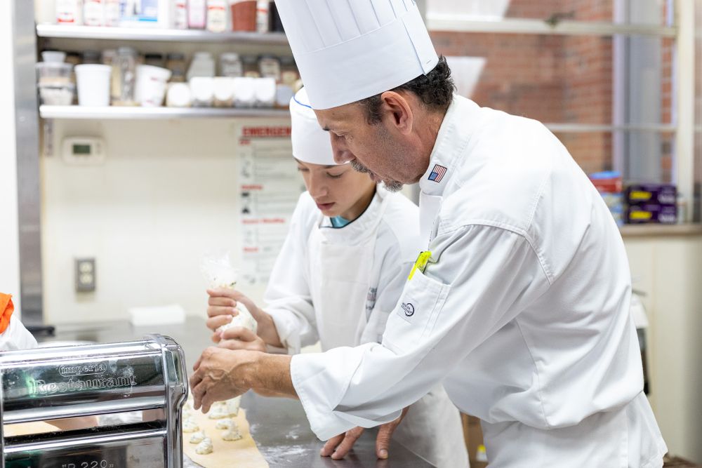 Chef Instructor teaching a student to press pasta dough