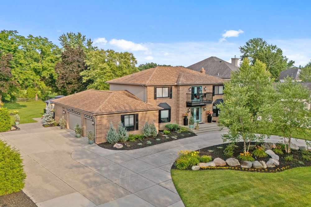 Stunning two-story brick home with a wide driveway, attached garage, and beautifully landscaped front yard.
