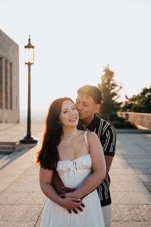 KC engagement session, man hugs women from behind and kisses cheek