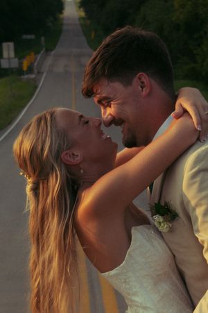 Bride and groom share a close embrace before a kiss smiling at each other.