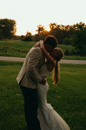 bride and groom share an intimate kiss while the sun sets over the trees.