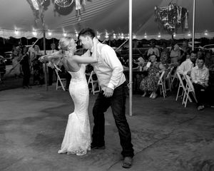 Bride and groom share first dance and do a spin full of movement while loved ones look on.