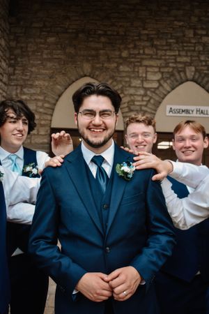 kansas city wedding photography, groom smiling with groomsman slapping back