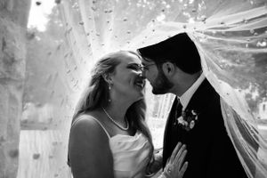 Bride and groom share a close embrace under bridal veil captured in black and white by kansas city wedding photographer