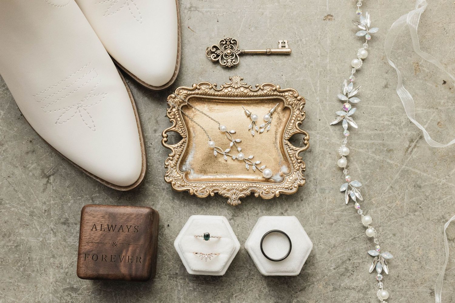 Vintage-style wedding details including keys, pearls, and decorative items on a textured surface.