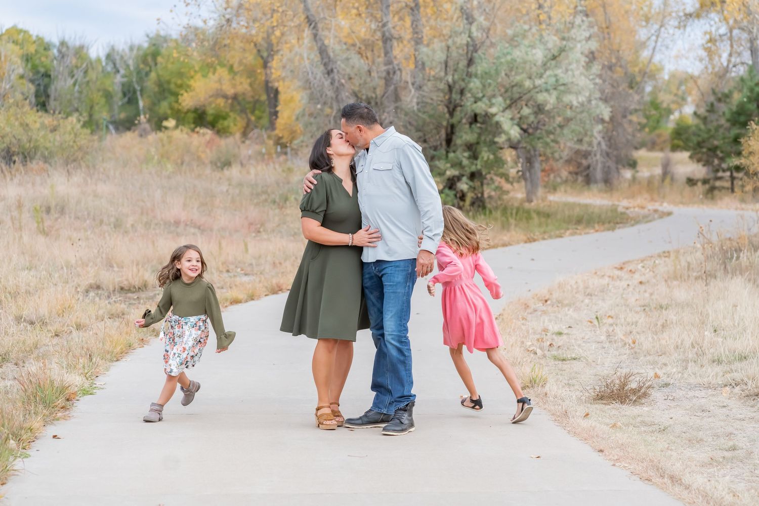 Sweet family moment captured on a path surrounded by autumn foliage.