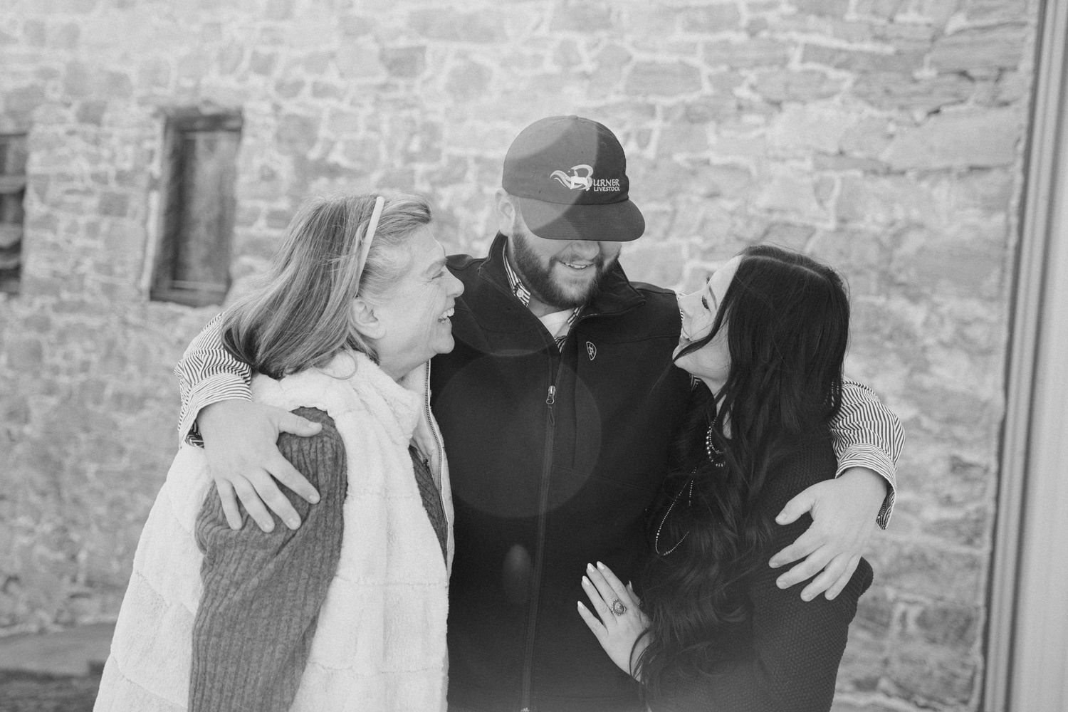 People embracing against a rustic stone wall background.