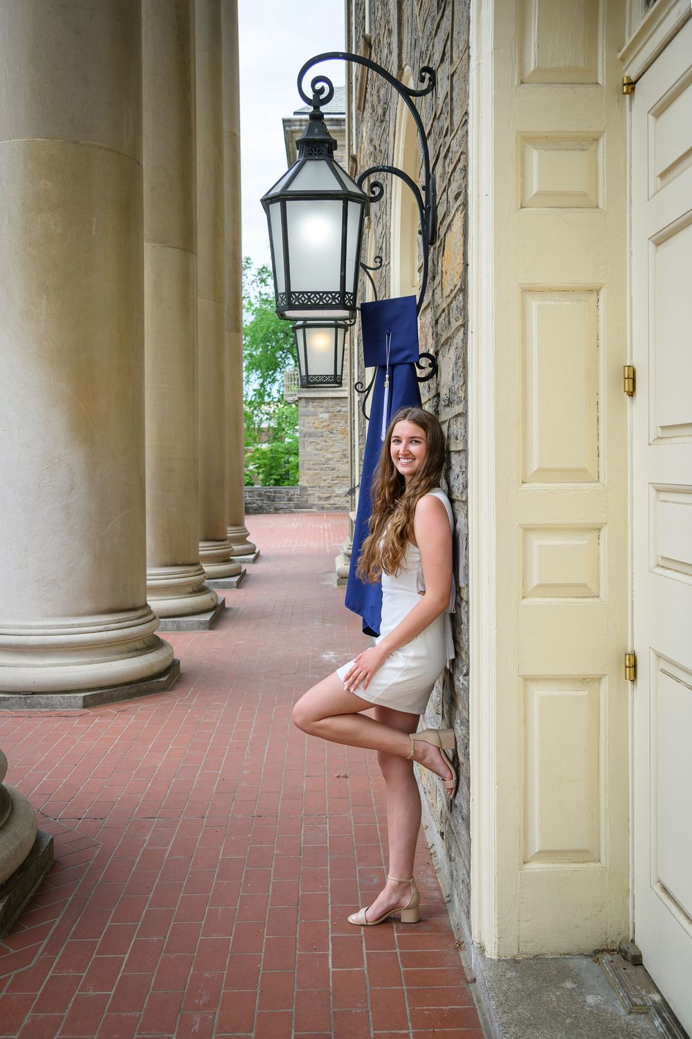 A series of architectural columns with lanterns frame a brick porch area in a classic building design.