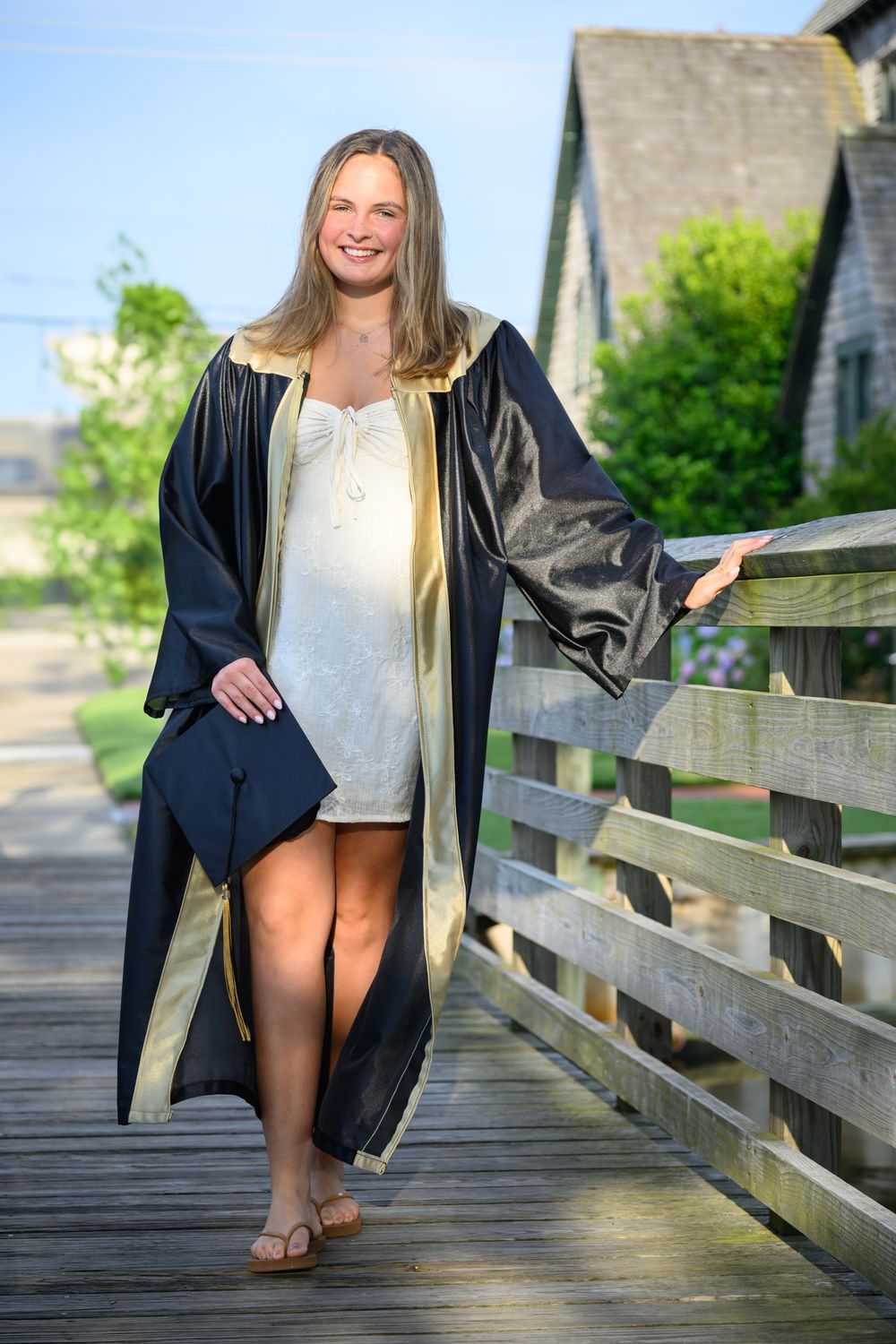 A person in graduation attire poses on a wooden boardwalk in a series of casual outdoor photos.