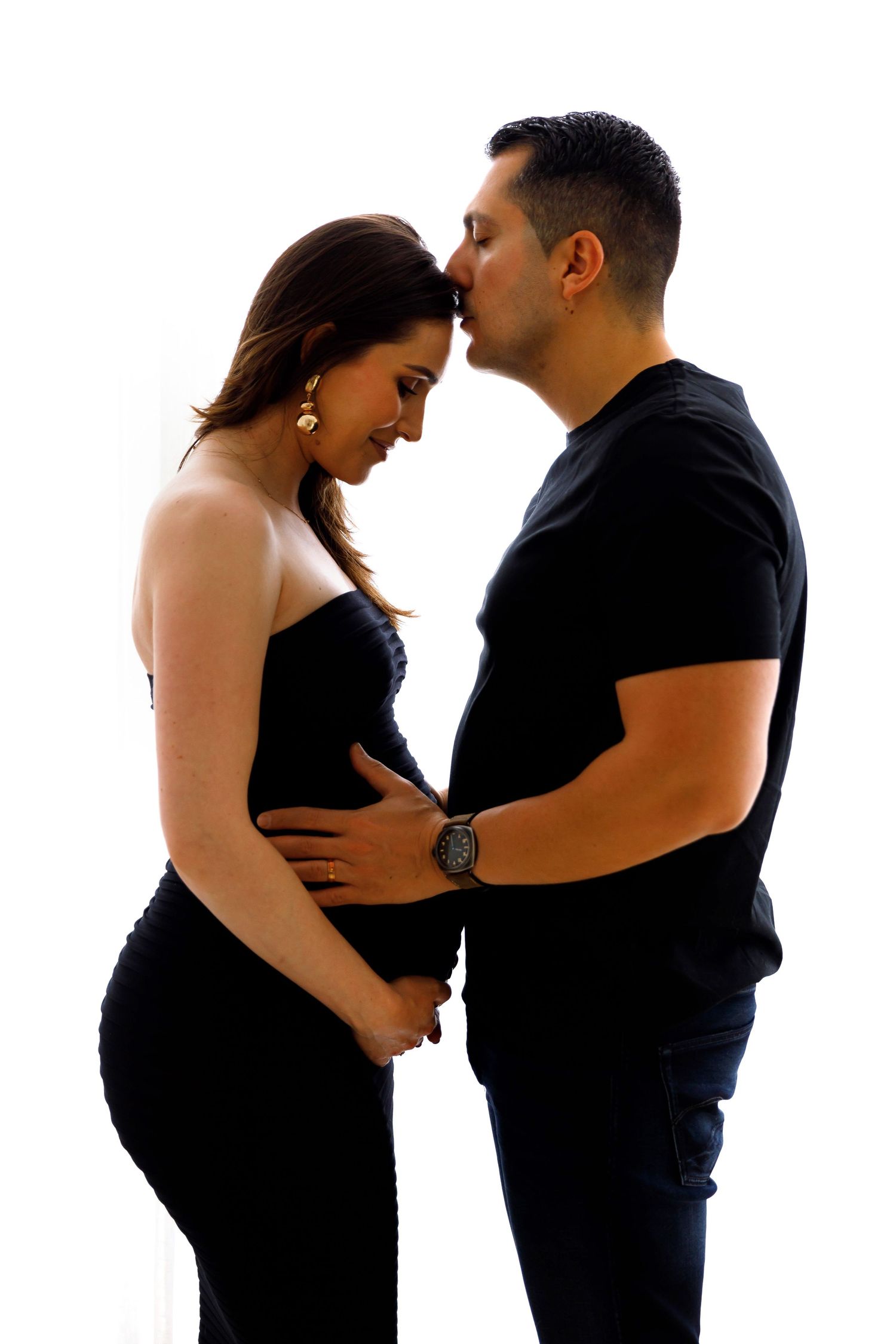 Silhouette of romantic couple sharing tender moment during pregnancy photoshoot.