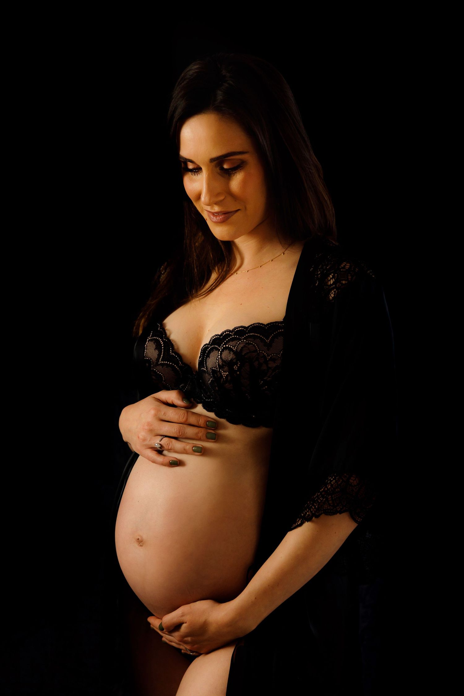 Intimate maternity portrait with warm lighting showcasing pregnancy in black lace.