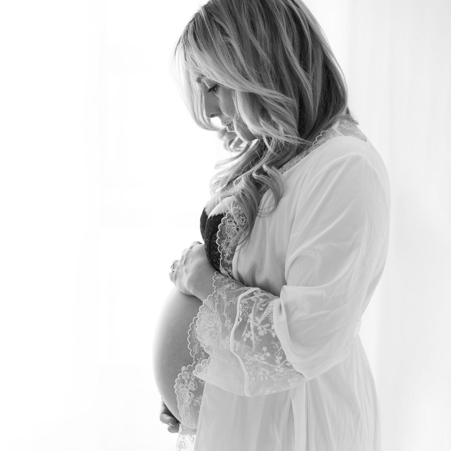 Romantic black and white maternity photo with flowing white lace robe.