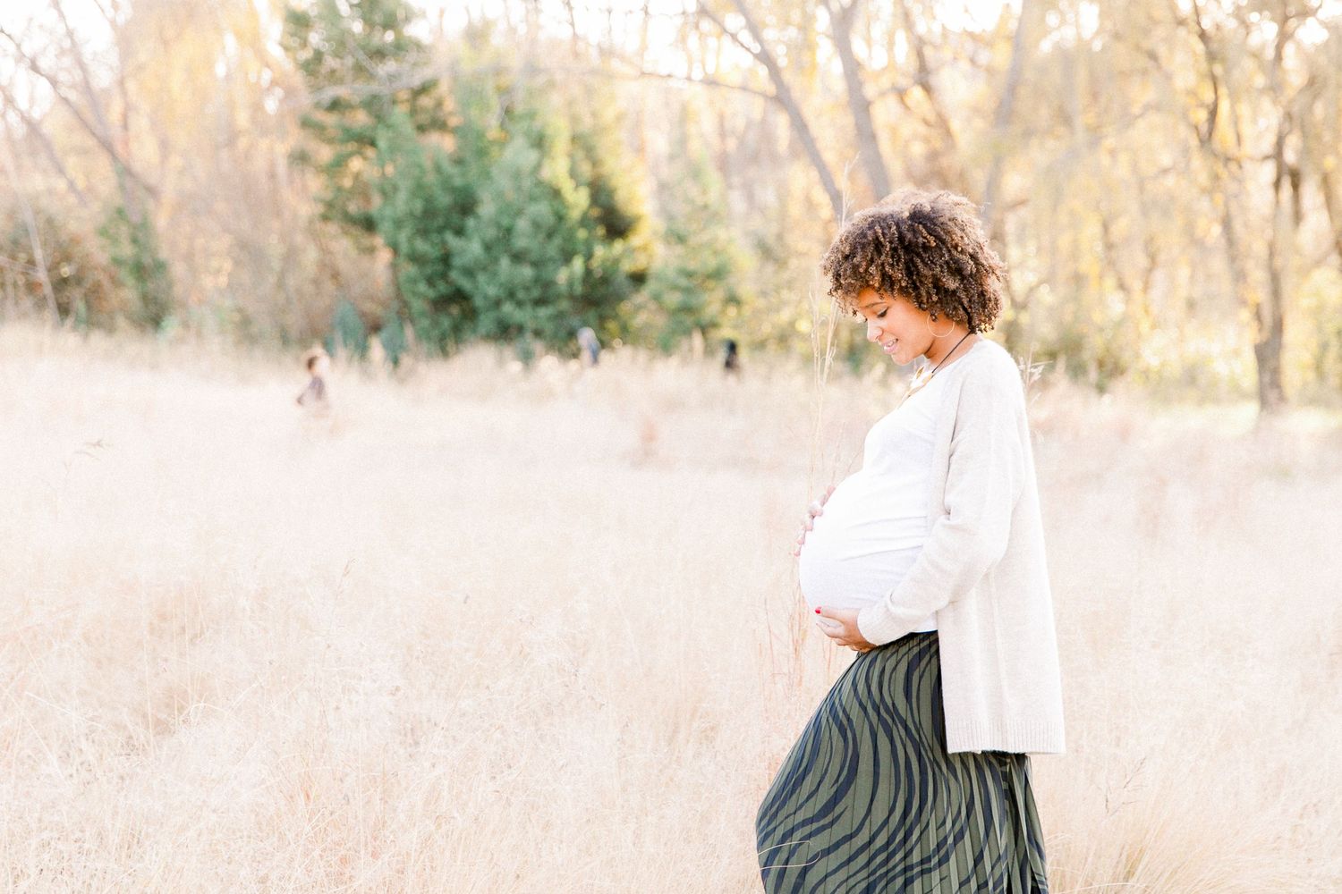 Serene maternity portrait in dreamy outdoor setting with tall grass.