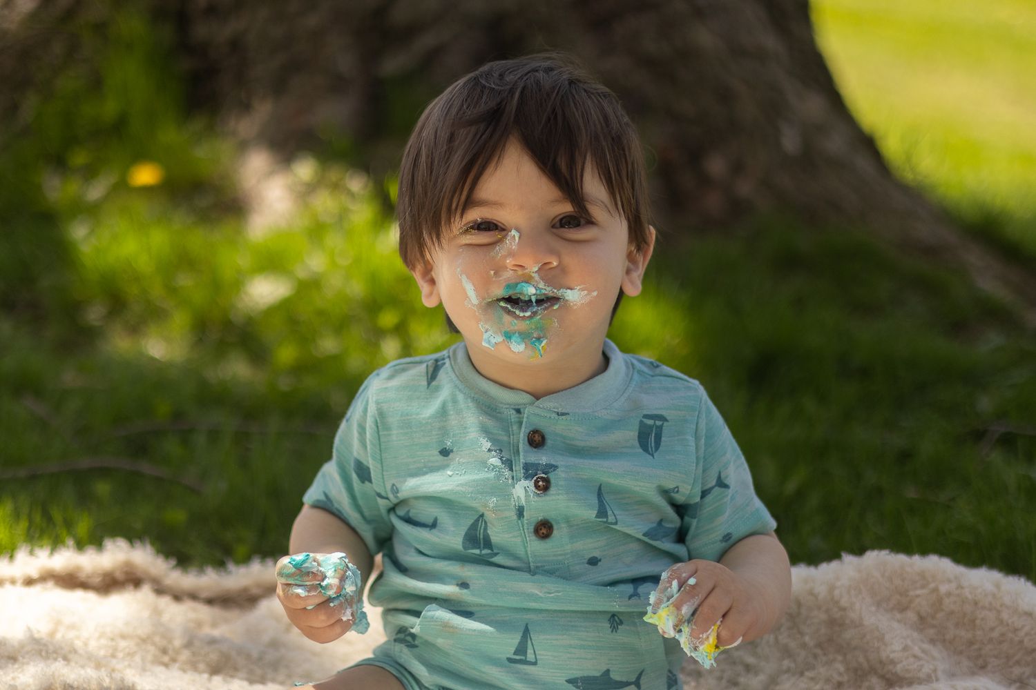 Baby Zayn face covered in icing enjoying his cake smash.