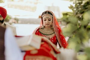 Close-up view of traditional Indian bridal jewelry and red wedding attire.