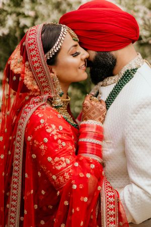 Intimate portrait of couple in traditional Sikh wedding attire sharing a tender moment.