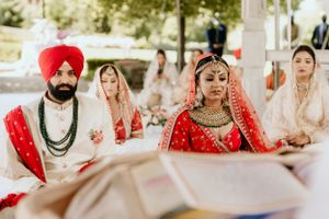 Traditional Sikh wedding ceremony with attendees seated outdoors under white tent.
