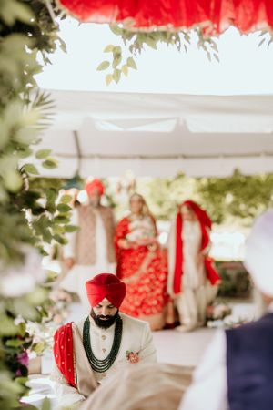 Outdoor Sikh wedding ceremony under white tent with traditional decor and floral arrangements.