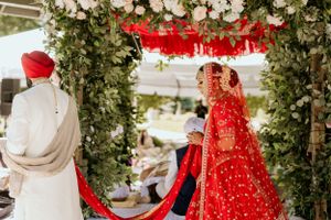 Wedding ceremony under arch decorated with white flowers and green foliage.
