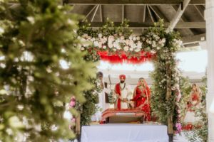 Traditional Indian wedding ritual conducted under a mandap decorated with flowers and greenery.