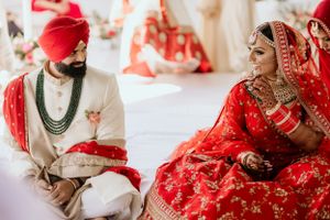 Traditional Indian wedding ceremony with white and red color scheme in outdoor setting.
