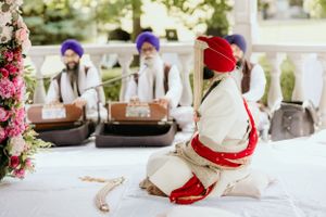 Traditional Sikh wedding ceremony with musicians playing instruments in white and red attire.