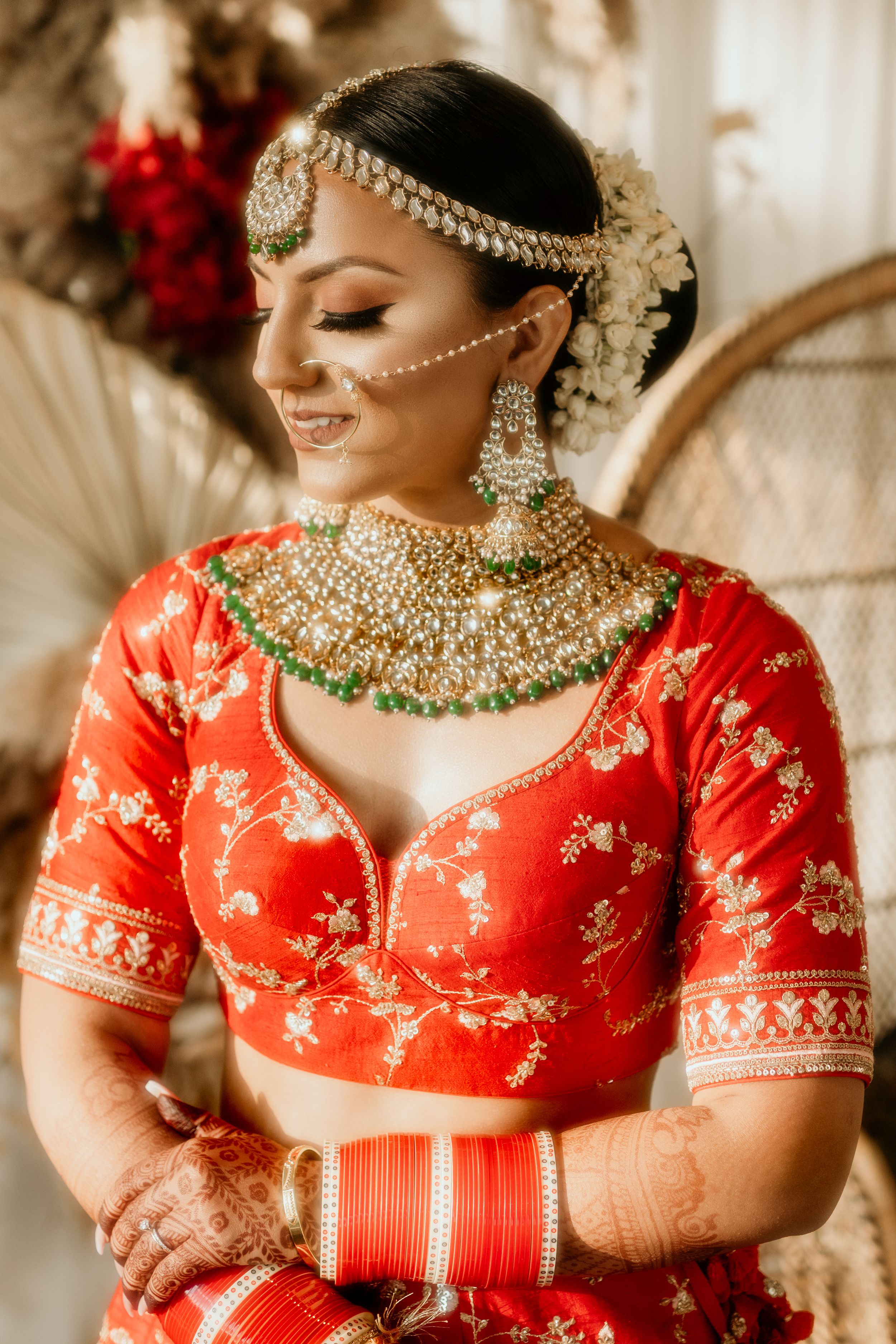 Traditional Indian bridal portrait showcasing ornate jewelry and a red embroidered lehenga.