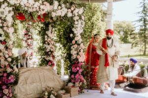 Wedding ceremony setup with floral arch adorned in white blooms and pink flowers.