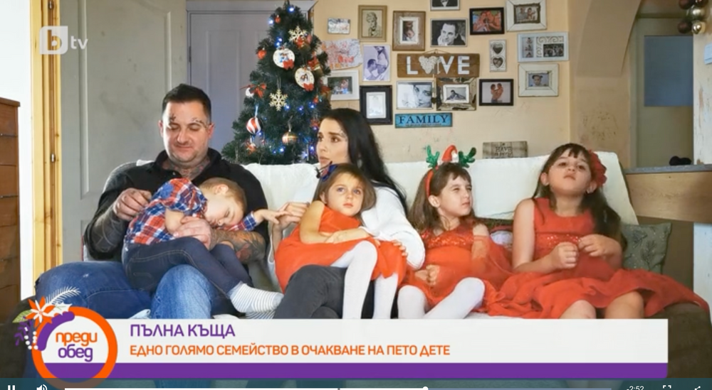 Family gathered on couch in front of decorated Christmas tree in living room.