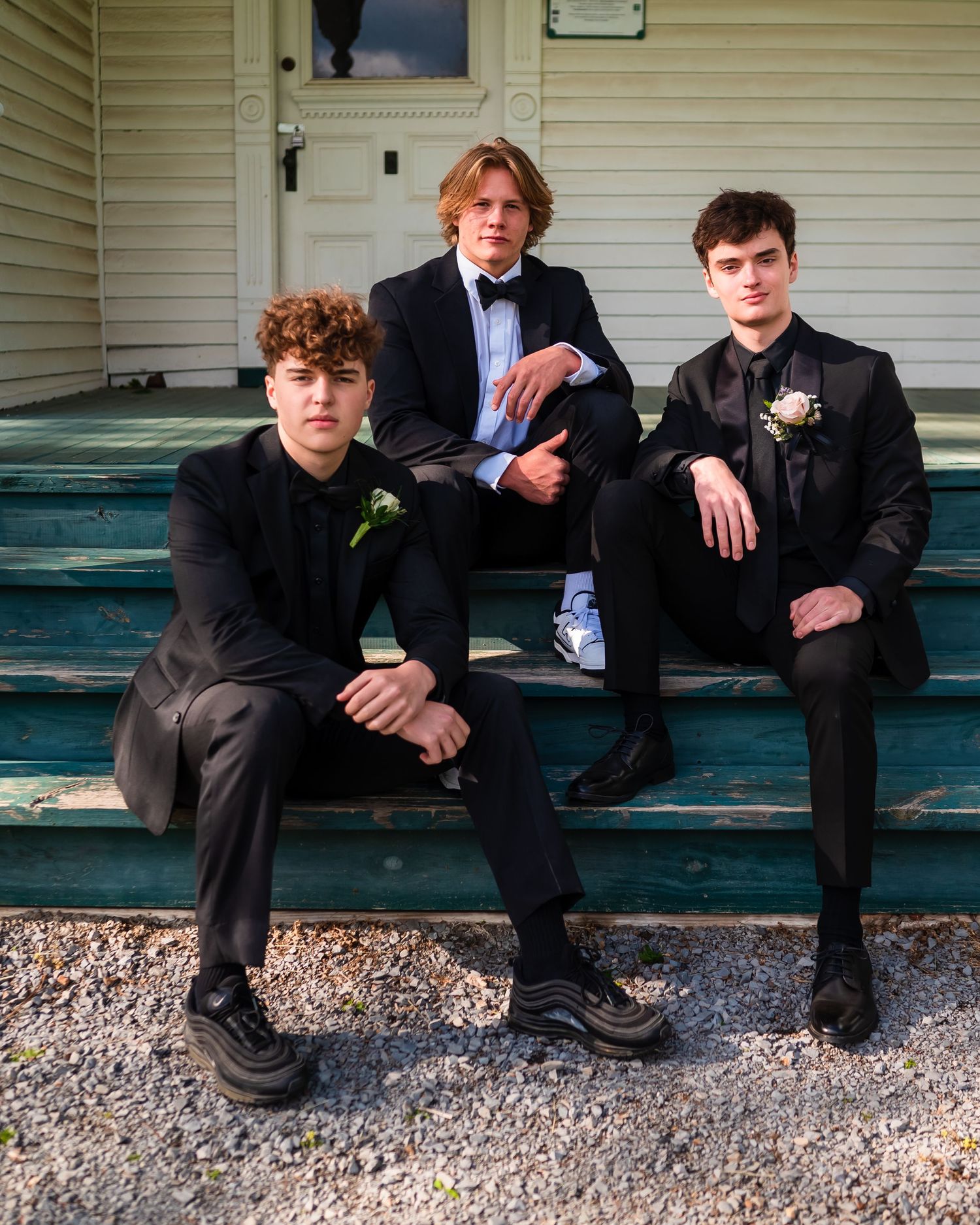Group of guys in formal wear relaxing on outdoor steps.