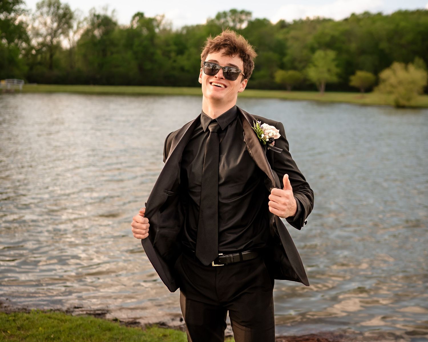 A formal photoshoot by a lakeside with someone in black attire making fun poses.