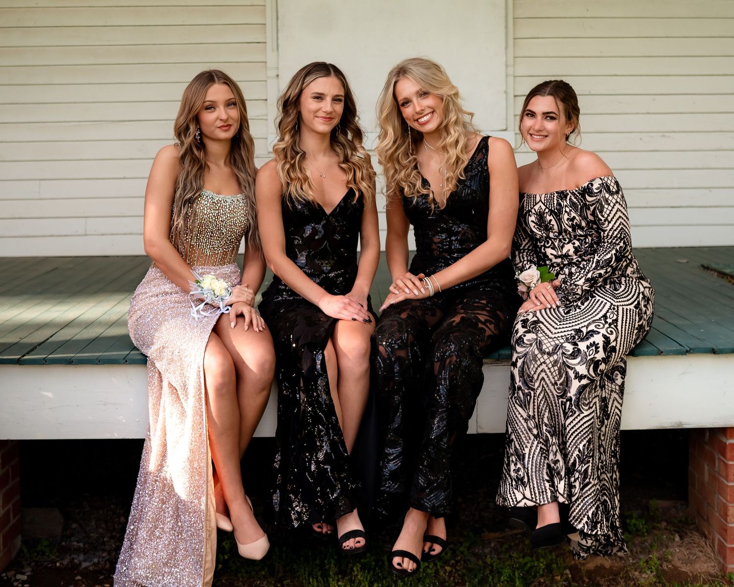 Group of friends in formal dresses pose together on porch steps.