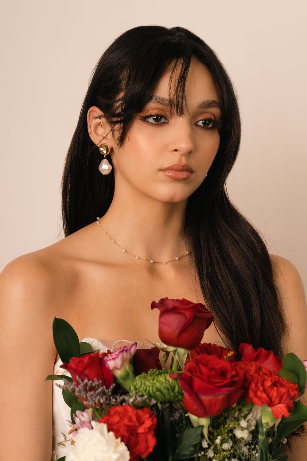 Bridal-inspired portrait of woman holding bouquet with soft makeup and pearl earrings – New York photo session.