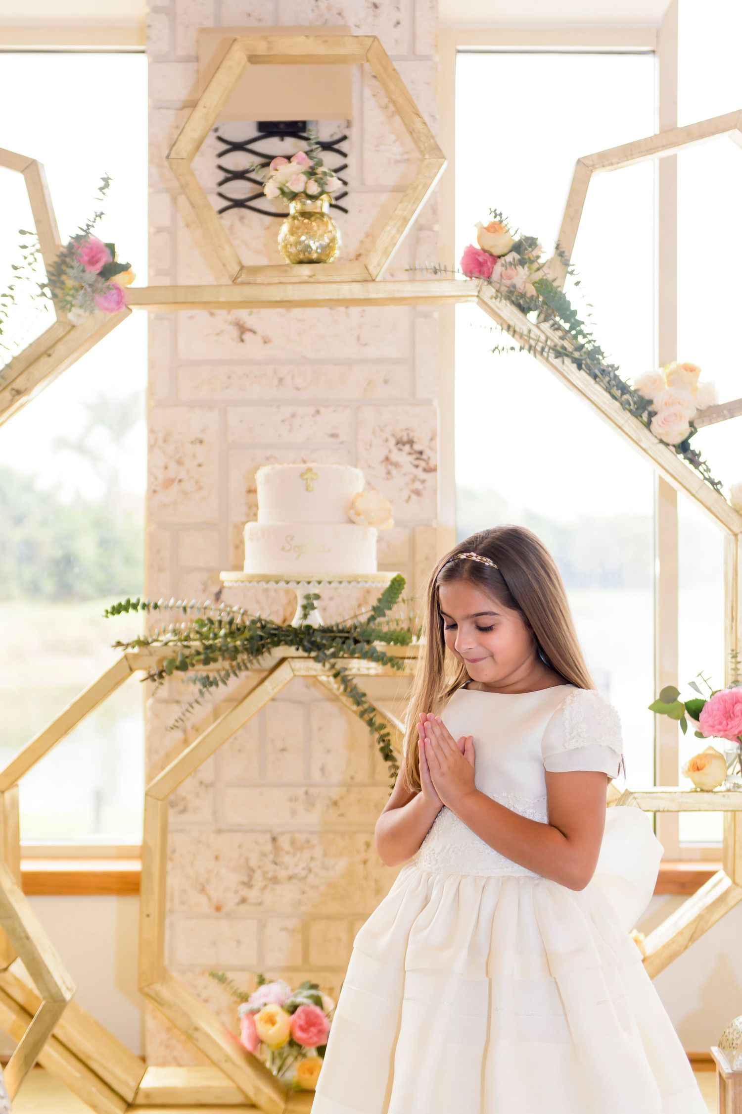 Decorative hexagonal display with white cake and pink floral arrangements.