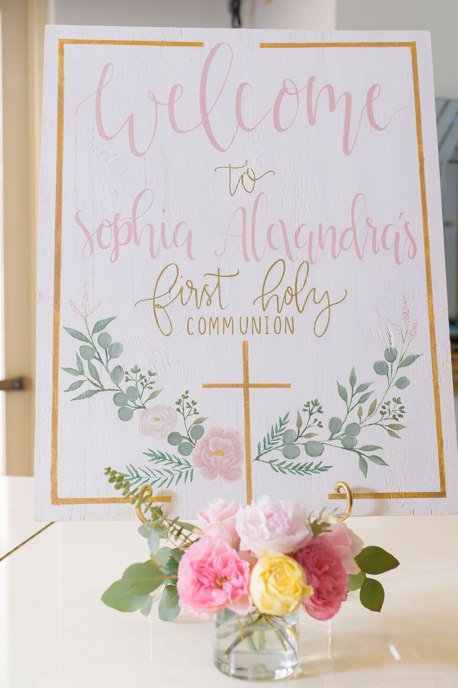 First Holy Communion welcome sign with pink calligraphy and floral decorations.