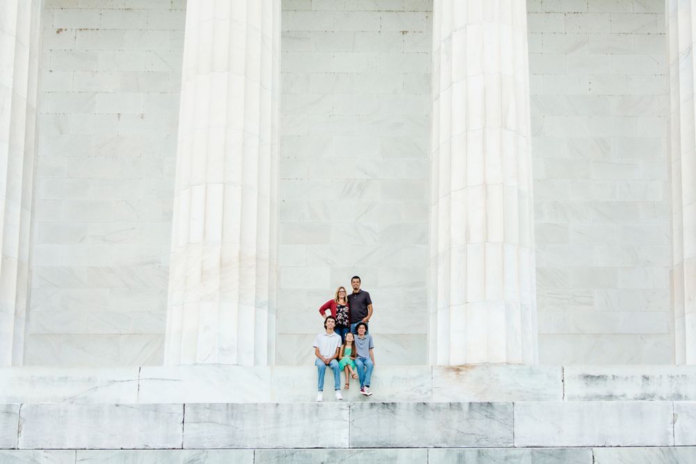 A family between tall white marble columns at the Lincoln Memorial in Washington DC, by Justin Baker Photography.