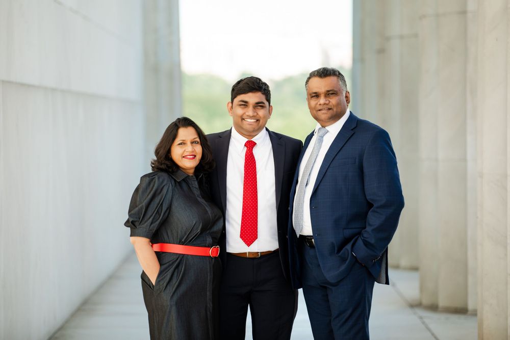 Family of three in business attire pose confidently against marble columns at DC monument, by Justin Baker Photography.