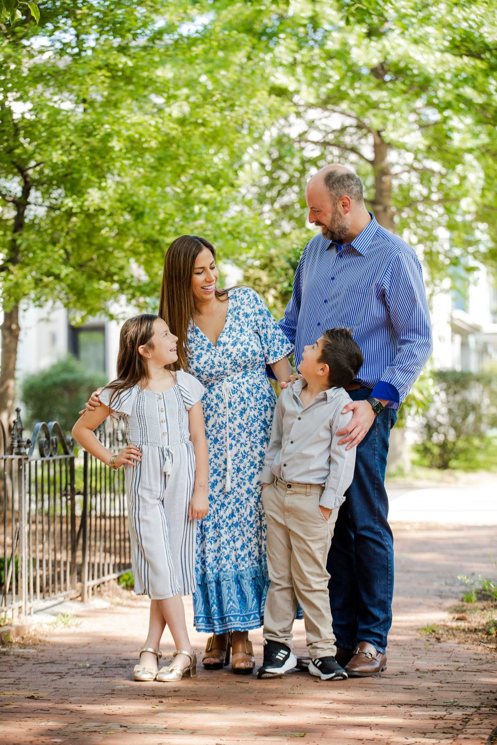A family enjoys a walk together on a tree-lined path, wearing coordinated blue and neutral colored outfits in Washington DC.
